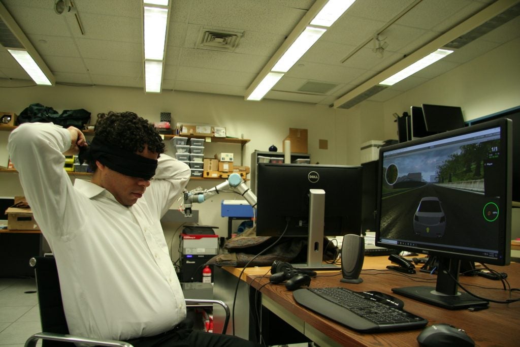 Brian Smith ties a strip of light absorbing blackout cloth around his eyes as a blindfold. He made a user interface so blind players can play racing games, and tested it with blind volunteers, and blindfolded sighted volunteers. 