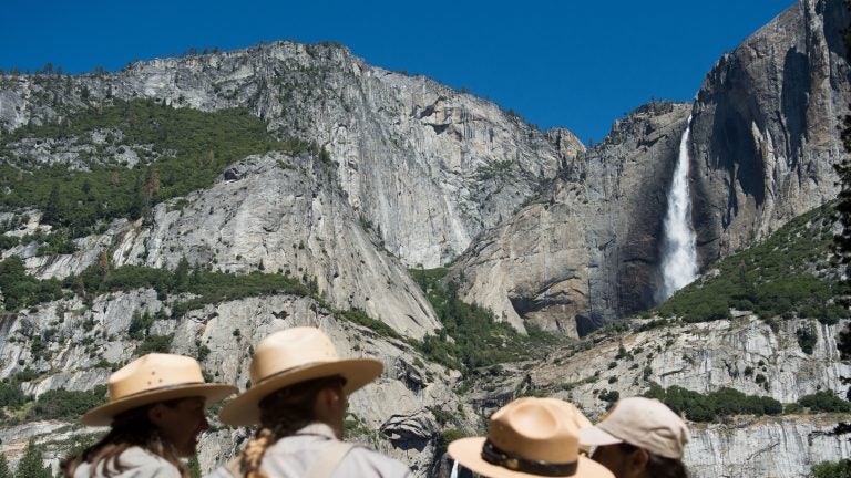 Park rangers meet in front of Yosemite Falls in 2016 in Yosemite National Park in California. Increased fees are expected to boost funding for park maintenance across the country. (David Calvert/Getty Images)