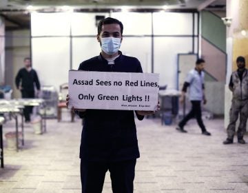 A medical worker at a Damascus hospital holds a sign protesting a suspected chemical weapons attack outside the Syrian capital a year ago. The suspected attacks led the U.S. to fire a barrage of missiles at a Syrian air base on April 7, 2017. (Sameer Al-Doumy/AFP/Getty Images)