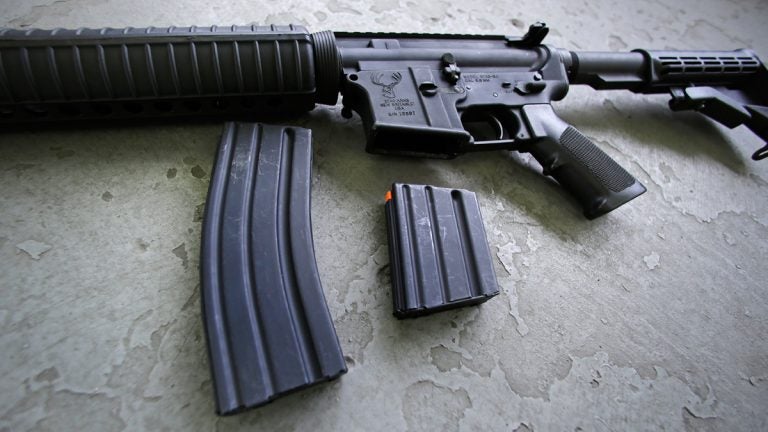 A 30-round magazine, left, and a 10-round magazine (right) rest below an AR-15 rifle. (AP Photo/Charles Krupa)