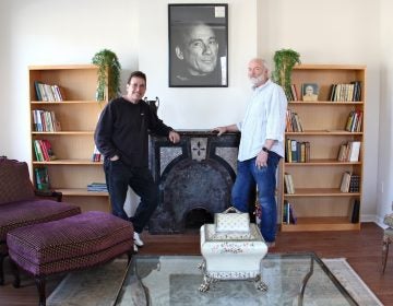 George Vallianos (left), president of the Nick Virgilio Haiku Association, and board member Henry Brann, stand beneath a portrait of the poet at the Nick Virgilio Writers House in Camden.