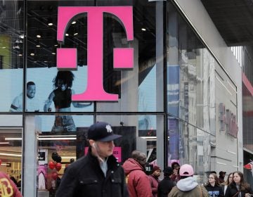Pedestrians walk past a T-Mobile store in New York City on Friday. Sprint and T-Mobile are seeking to merge, but the proposed deal sill requires regulatory approval.