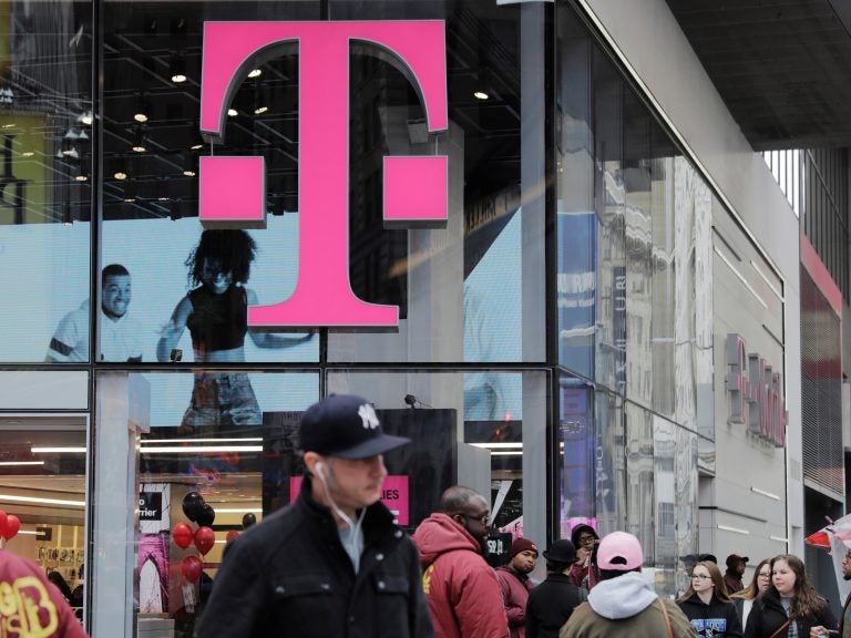 Pedestrians walk past a T-Mobile store in New York City on Friday. Sprint and T-Mobile are seeking to merge, but the proposed deal sill requires regulatory approval.