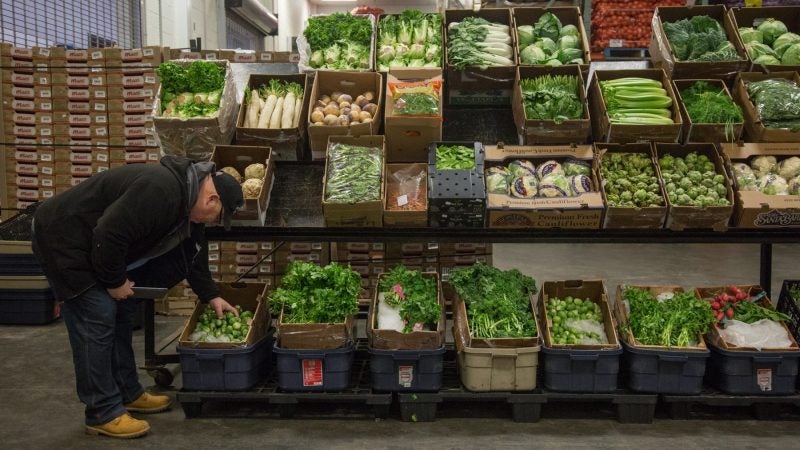 Jimmy inspects some Brussels sprouts at one of the produce vendors inside the wholesale center. (Emily Cohen for WHYY)