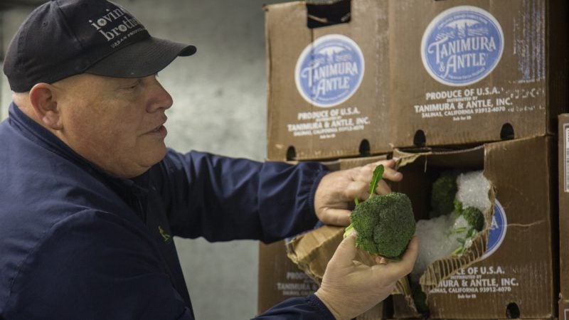 Jimmy inspects some of the broccoli he just purchased after it arrives back at his market. (Emily Cohen for WHYY)