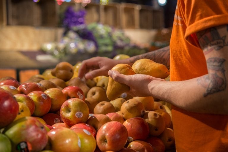 Alex Veal, 28, stacks some pears at Iovine Brothers produce store in Reading Terminal Market.