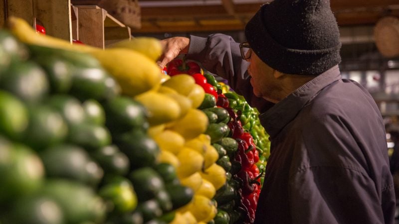 A shopper picks up some produce in the precisely stacked shelves of Iovine Brothers. (Emily Cohen for WHYY)