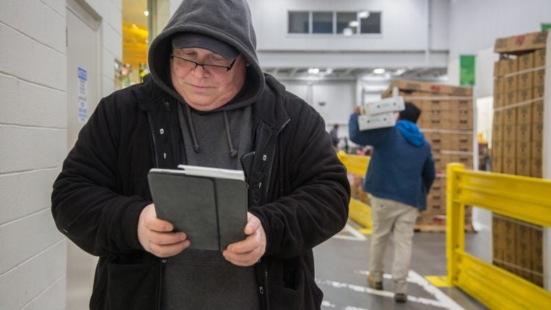 After making a purchase at one of the many vendors at the wholesale center, Jimmy enters the information into his Google Sheets document as he walks to the next vendor. (Emily Cohen for WHYY)