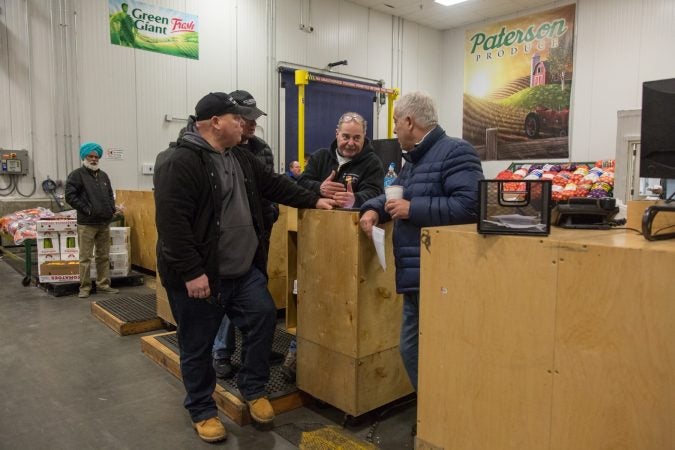 Jimmy chats with some other buyers and vendors about a new trucking policy that may affect their prices and businesses. (Emily Cohen for WHYY)