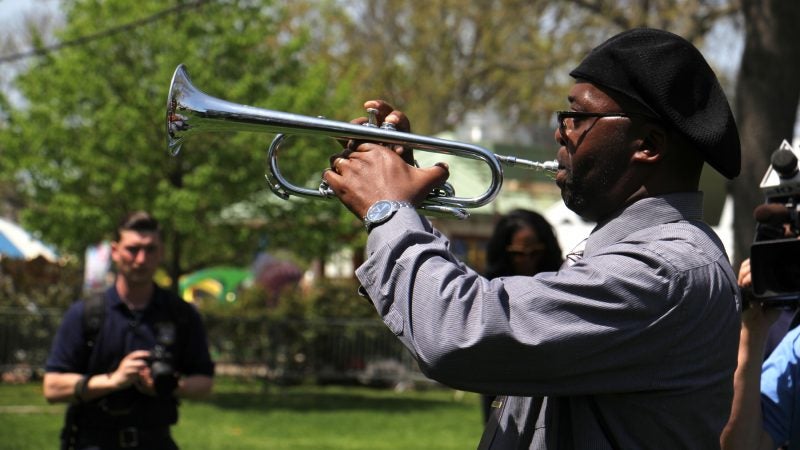 Retired Philadelphia police officer Ronald Baker plays taps during the Living Flame Memorial Service at Franklin Square. (Emma Lee/WHYY)