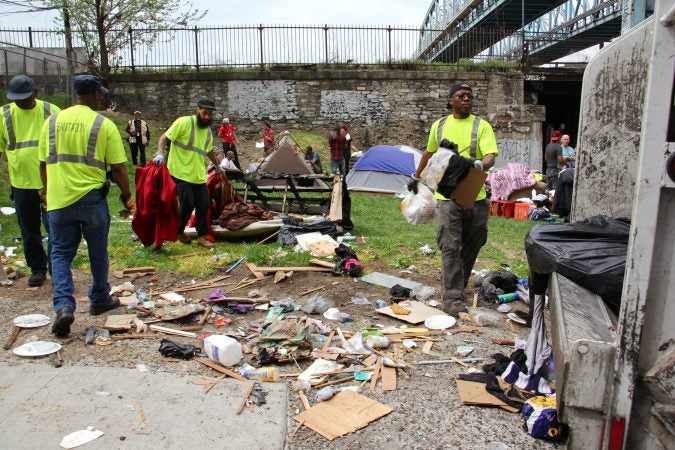 Sanitation workers clear away mounds of garbage from a heroin encampment at Lehigh and Kensington avenues. (Emma Lee/WHYY)