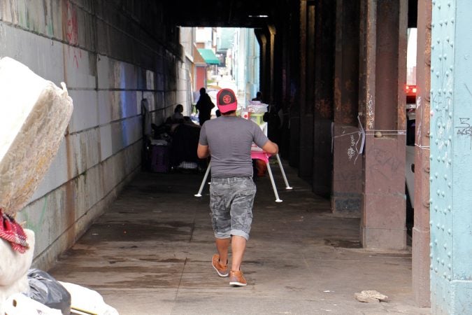 After city sanitation workers finish cleaning, campers move back under the railroad overpass. (Emma Lee/WHYY)