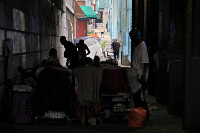 After city sanitation workers are done cleaning, campers move back under the railroad overpass. (Emma Lee/WHYY)