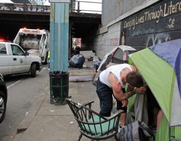 A visitor to the Kensington Avenue heroin encampment checks on a friend. (Emma Lee/WHYY)