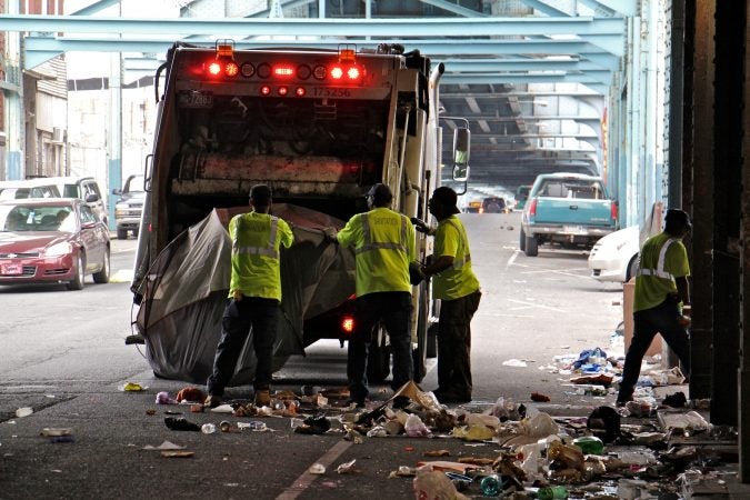 Sanitation workers clear away mounds of garbage from a heroin encampment at Lehigh and Kensington avenues. (Emma Lee/WHYY)