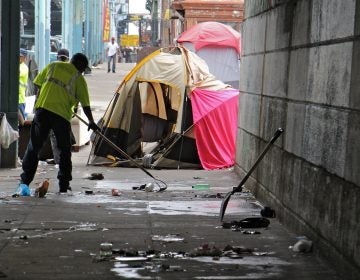 Sanitation workers clear away mounds of garbage from a heroin encampment at Lehigh and Kensington avenues. (Emma Lee/WHYY)