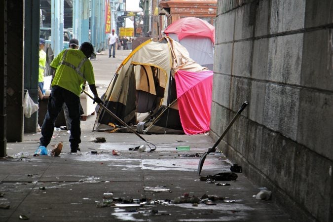 Sanitation workers clear away mounds of garbage from a heroin encampment at Lehigh and Kensington avenues. (Emma Lee/WHYY)