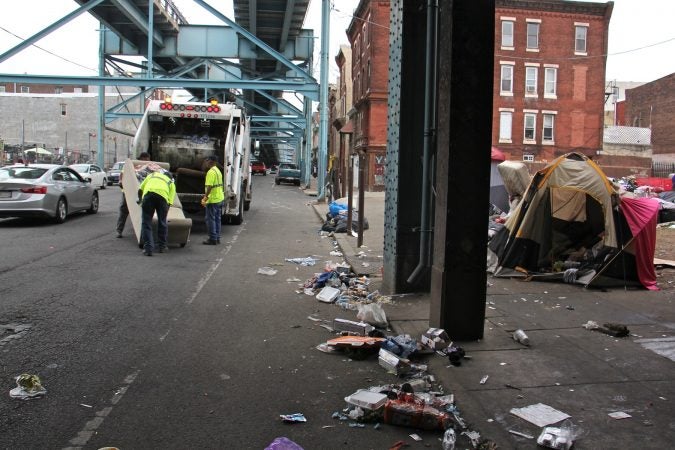 Sanitation workers clear away mounds of garbage from a heroin encampment at Lehigh and Kensington avenues. (Emma Lee/WHYY)