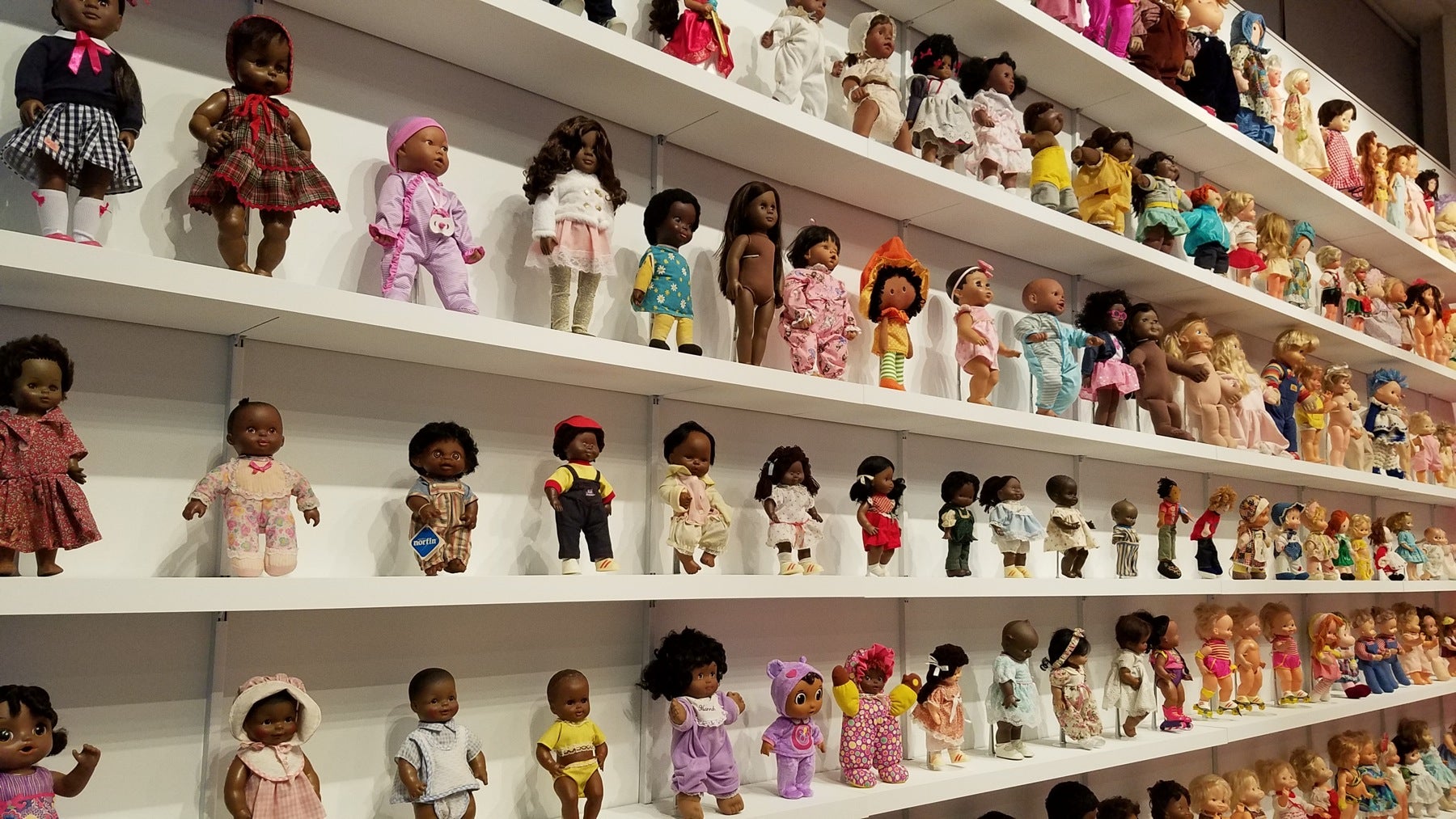 Whiteman’s dolls, on the left side of the wall, are all black. Hancock’s on the right are all white. 