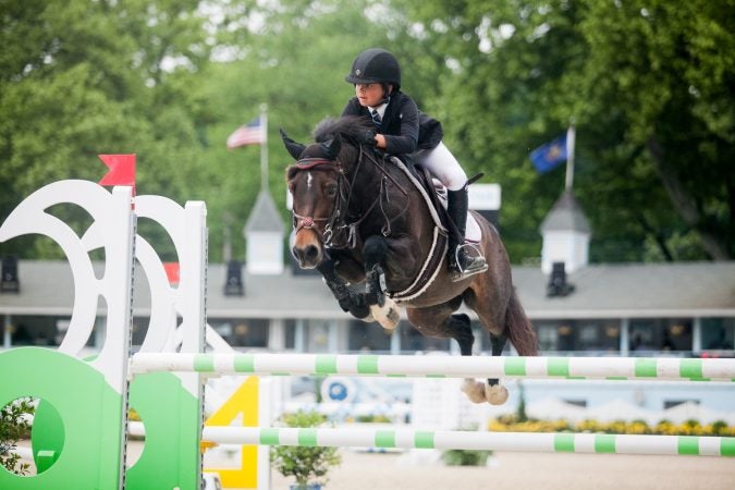 Austin Bauman jumps her horse Miracles Happen at the 122nd annual Devon Horse Show Sunday, May 27. (Brad Larrison for WHYY)