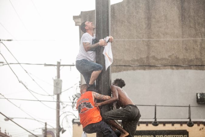 As a heavy rain started to fall the South Philly team who has competed in past years tries to climb the grease pole anyway. (Brad Larrison for WHYY)