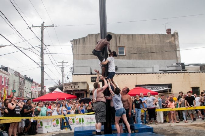 An impromptu of team of strangers attempted to climb the grease pole at the Italian Market Festival Sunday. (Brad Larrison for WHYY)