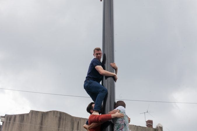 A team dubbed David's Mighty Men ascended the grease pole at the Italian Market Festival Sunday. (Brad Larrison for WHYY)