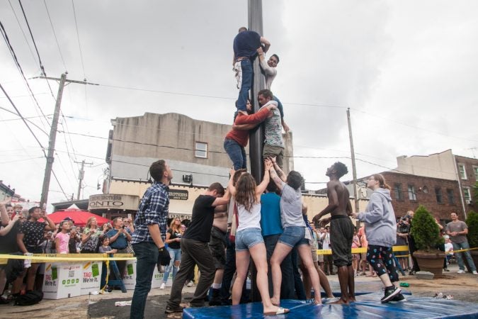 A team dubbed David's Mighty Men ascended the grease pole at the Italian Market Festival Sunday. (Brad Larrison for WHYY)