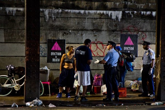 Philadelphia police speak to residents of a homeless encampment at Kensington and Lehigh avenues before a scheduled clean out in May 2018. (Kimberly Paynter/WHYY)