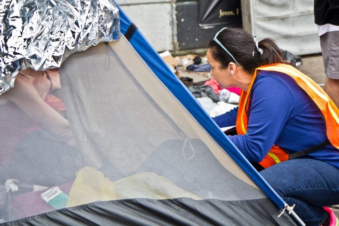 An outreach worker speaks to residents of a homeless encampment at Kensington and Lehigh avenues about half an hour before a scheduled clean out. (Kimberly Paynter/WHYY)