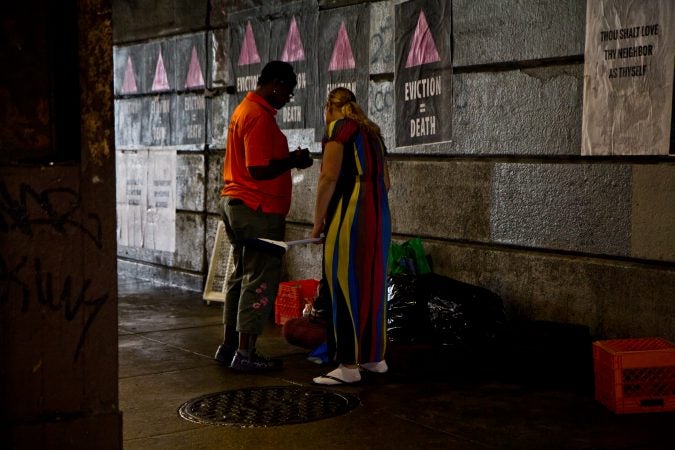 An outreach worker speaks to residents of a homeless encampment at Kensington and Lehigh avenues about half an hour before a scheduled clean out. (Kimberly Paynter/WHYY)