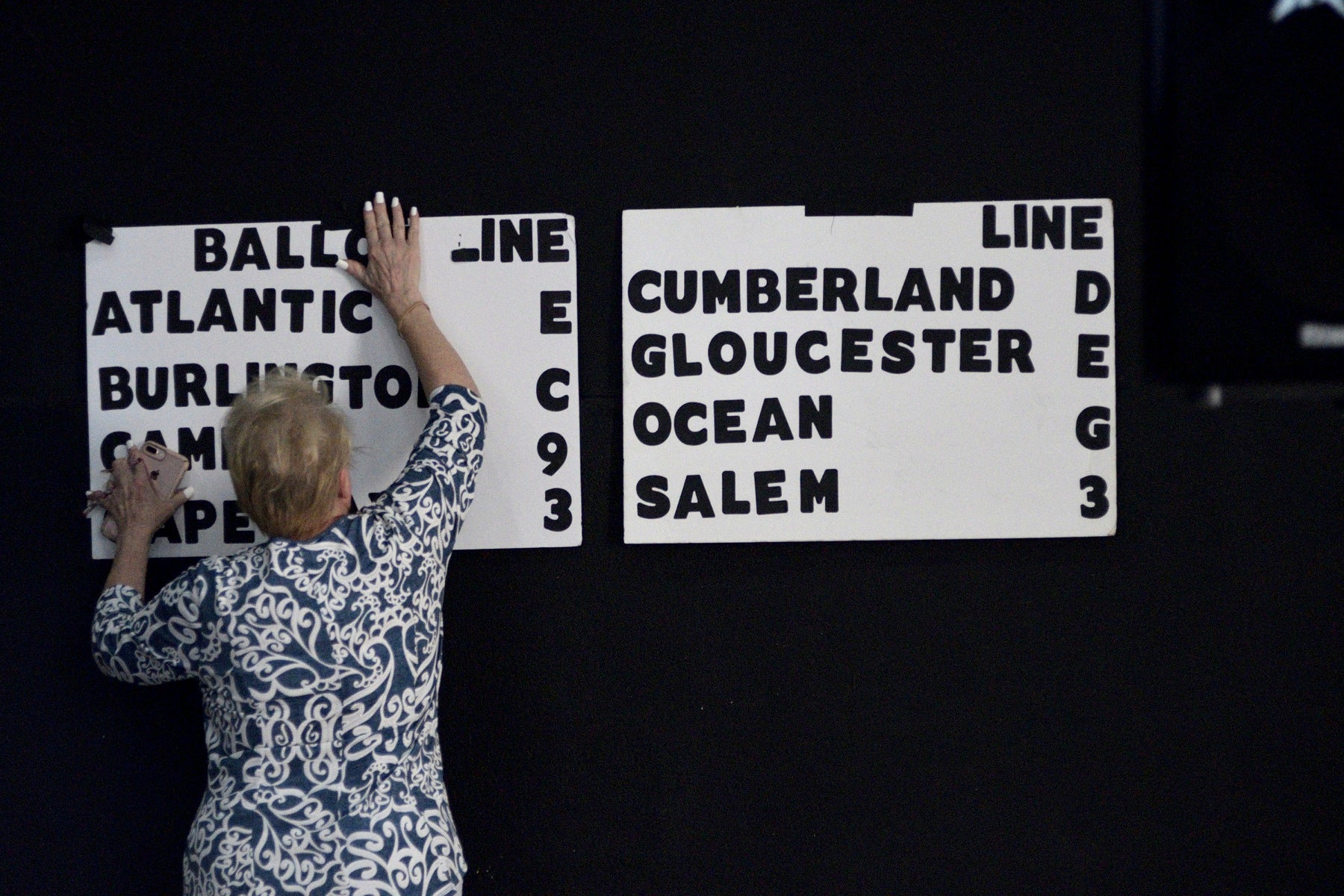 Campaign volunteer Helen Duda mounts a board indicating the candidate's position on the eight different ballots for the upcoming congressional primaries. 