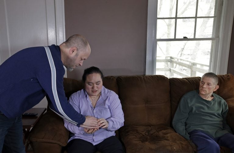 In this March 5, 2018 photo, Wil Darcangelo, (left), speaks with his 22-year-old adopted daughter, Lavender, who is blind and autistic, while friend and housemate, Christoph Malvaney, listens at their home. 