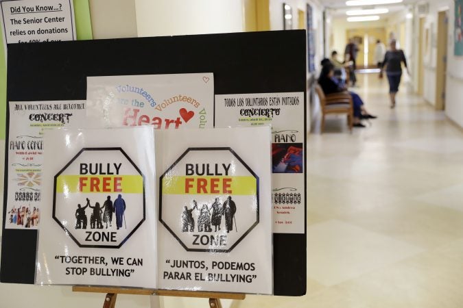 In this Friday, April 13, 2018 photo, signs promote a bully-free environment at the On Lok 30th Street Senior Center in San Francisco. After problems at the facility, all staff members received 18 hours of training that included lessons on what constitutes bullying, causes of the problem and how to manage such conflicts. Seniors were then invited to similar classes teaching them to alert staff or intervene themselves if they witness bullying. (Marcio Jose Sanchez/AP Photo)
