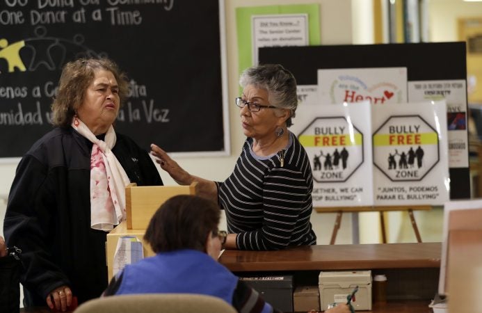 In this Friday, April 13, 2018 photo, two women talk in front of anti-bullying signs at the On Lok 30th Street Senior Center in San Francisco. After problems at the facility, all staff members received 18 hours of training that included lessons on what constitutes bullying, causes of the problem and how to manage such conflicts. Seniors were then invited to similar classes teaching them to alert staff or intervene themselves if they witness bullying. (Marcio Jose Sanchez/AP Photo)