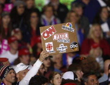 An audience member holds a fake news sign during a President Donald Trump campaign rally in Washington Township, Mich., Saturday, April 28, 2018.