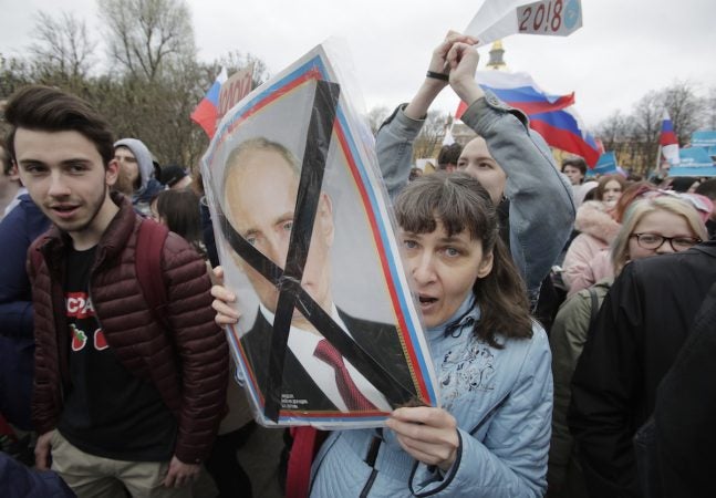 Demonstrator carries a poster depicting Russian President Vladimir Putin during a massive protest rally in St.Petersburg, Russia, Saturday, May 5, 2018. Alexei Navalny, anti-corruption campaigner and Putin's most prominent critic, called for nationwide protests on Saturday, two days ahead of the inauguration of Vladimir Putin for a fourth term as Russian president. (Dmitri Lovetsky/AP Photo)