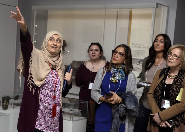 In this April 26, 2018 photo, Moumena Saradar, left, originally from Syria, guides visitors through the Middle East gallery at Penn Museum, in Philadelphia. The University of Pennsylvania Museum of Archaeology and Anthropology is in the midst of dramatic renovations, opening new galleries to showcase previously undisplayed items, telling the stories of those artifacts in more relatable ways and adding guides native to the parts of the world being showcased. (AP Photo/Jacqueline Larma)