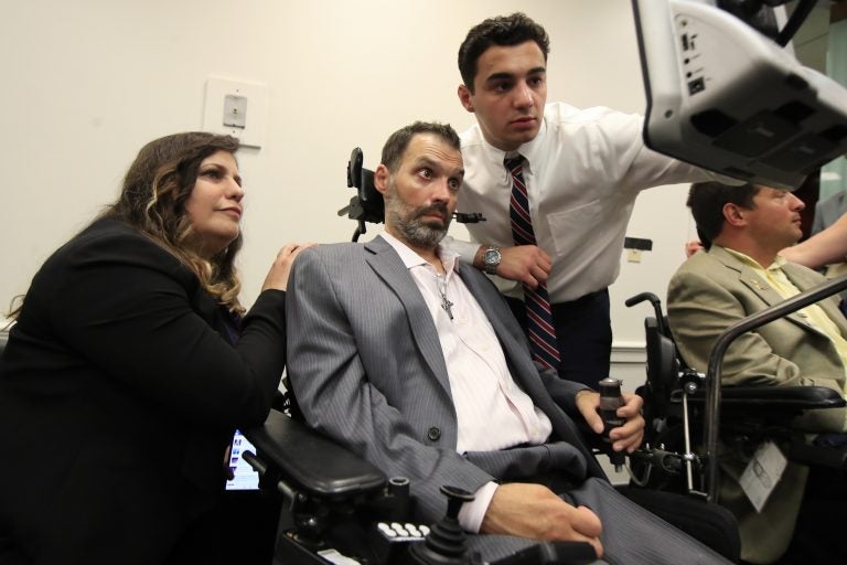 ALS patient Frank Mongiello communicates with his wife, Marilyn, and his son during a news conference following the passage of the 