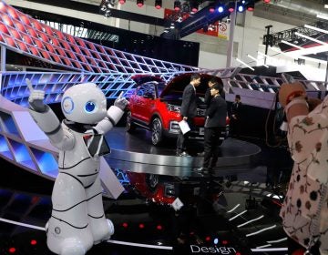 In this April 26, 2018, photo, a robot entertains visitors at the booth of a Chinese automaker during the China Auto 2018 show in Beijing, China. Under President Xi Jinping, a program known as 