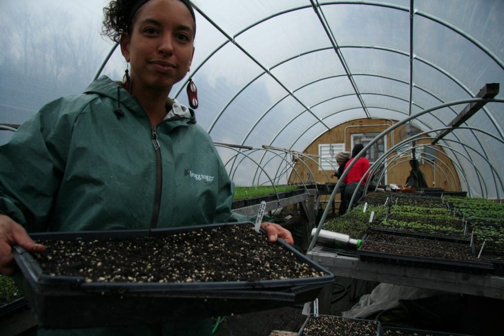 Farmer Leah Penniman holds a tray of soil with seeds. She grows plants that help her connect to her Afro-indigenous roots. (Alan Yu/WHYY)