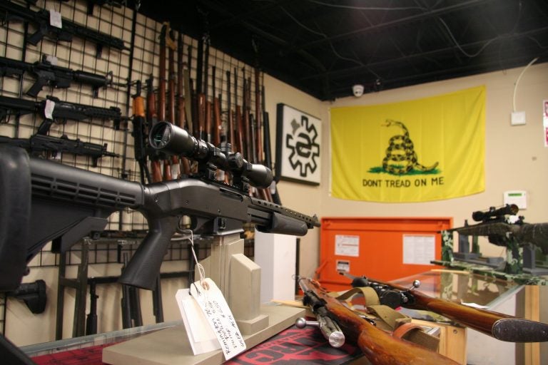 A display of rifles in a gun shop, with a flag that says 