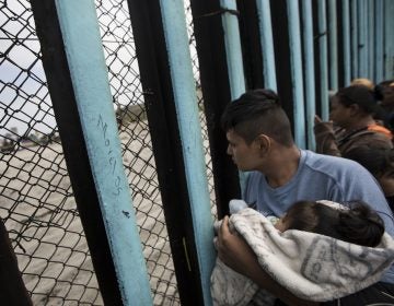 Central American migrants look through the border wall near the ocean in Tijuana, Mexico, in April.