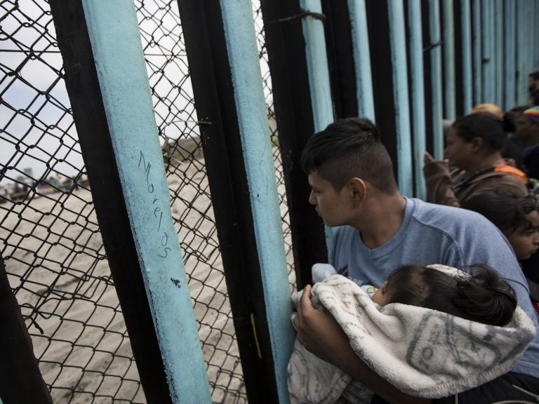 Central American migrants look through the border wall near the ocean in Tijuana, Mexico, in April.