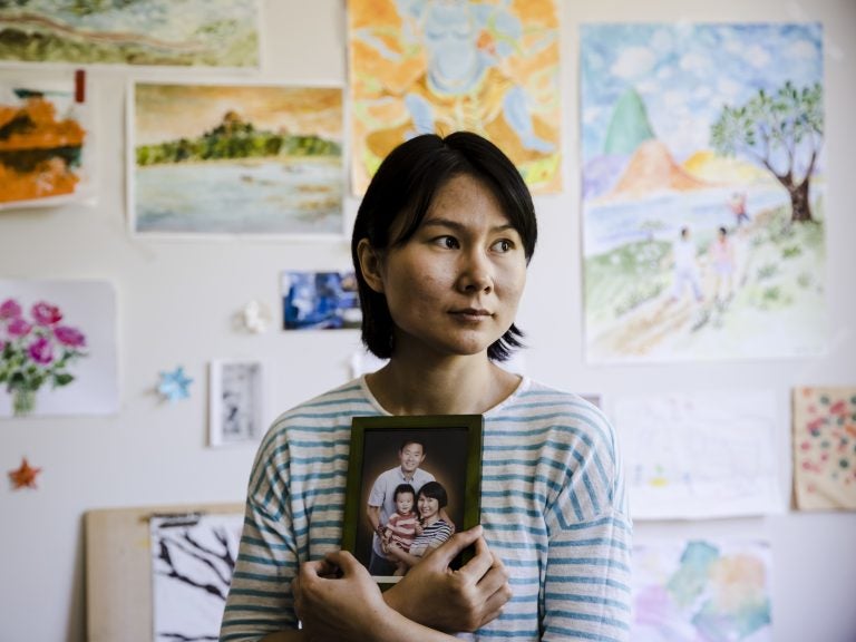 Hua Qu, the wife of Chinese-American Xiyue Wang, poses with a portrait of her family in Princeton, N.J., on May 9. Families of Americans detained in Iran are hoping President Trump's decision to withdraw from the Iran nuclear deal will not make it harder to get their love ones freed. (Matt Rourke/AP)