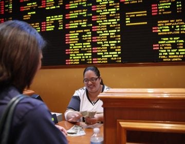 Crystal Kalahiki pays out a bet in the sports book at the South Point hotel-casino, Monday, May 14, 2018, in Las Vegas. The U.S. Supreme Court gave its go-ahead for states to allow gambling on sports across the nation, striking down a federal law that barred betting on football, basketball, baseball and other sports in most states. (John Locher/AP Photo)