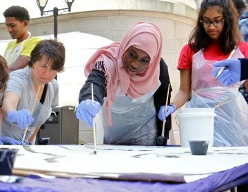 Masterman High School student Shahla Mukhtar (center) helps to paint a portion of the Octavius Catto mural.