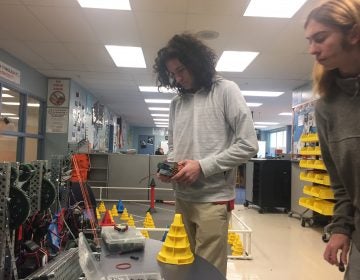 Dickinson High junior Jeremy Nolan works on his robot as partner Ian Shotwell observes. (Cris Barrish/WHYY)