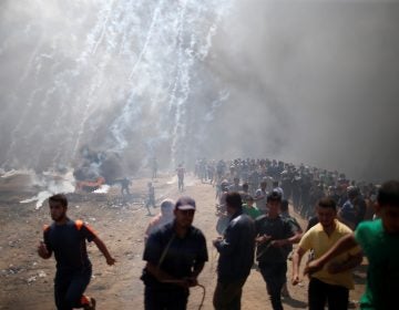 Palestinian demonstrators run from tear gas fired by Israeli troops during a protest against the U.S. embassy move to Jerusalem and ahead of the 70th anniversary of Nakba, at the Israel-Gaza border east of Gaza City.
