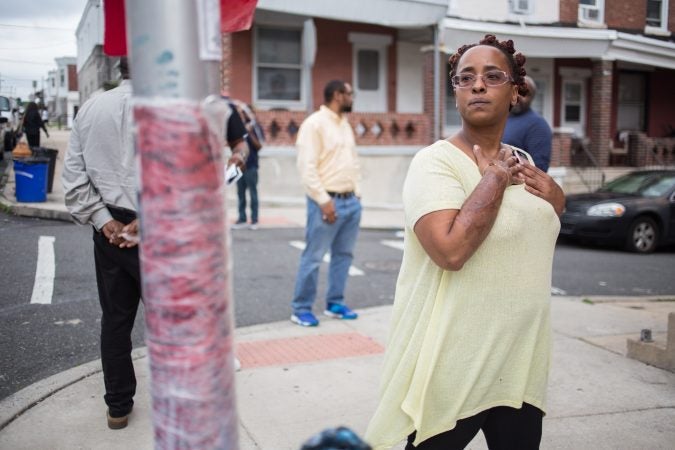 Malika Lovelace, who works for the Philadelphia Anti-Drug/Anti-Violence Networ,k looks at a makeshift memorial at the site where 17-year-old Sandrea Williams was shot to death in her mother’s West Philadelphia neighborhood. (Emily Cohen for WHYY)